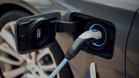 An electric car charging: a plug-in cable is inserted into the charging port inside the vehicle.