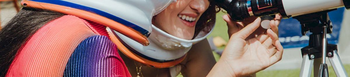 a woman wearing a helmet looking through a telescope